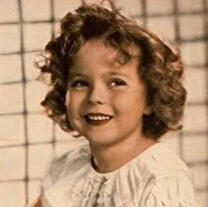 Photo of Shirley Temple from the 1930s old photo of Shirley Temple as a young girl, small circular image with Shirley Temple's head and shoulders in frame. Gir with red curly hair, smiling and looking just off to the side of the camera. She's wearing a white frilly dress.